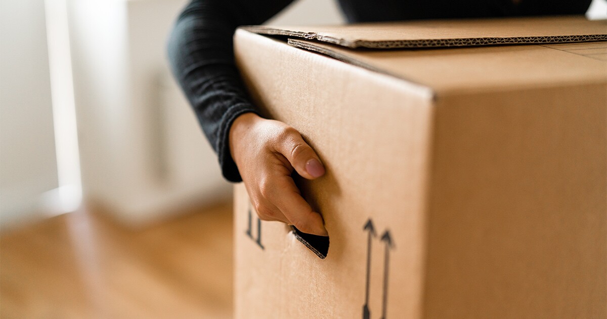 A person carries a moving box.