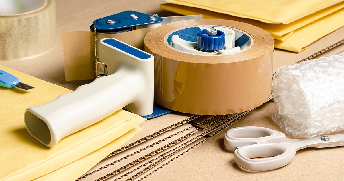 Various packing supplies including moving tape, scissors and bubble wrap.